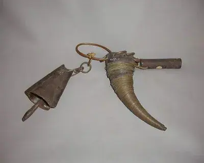 Amulette constituée d'une corde entourée de fil de laiton, d'une clochette en fer forgé et d'un petit cylindre en bois