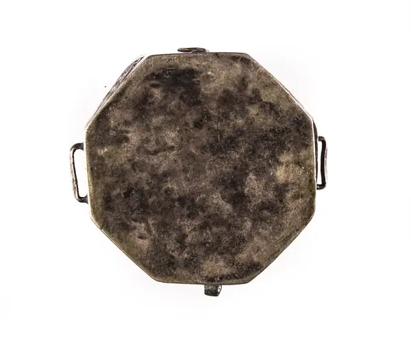 Cutie-amuletă destinată păstrării unui coran miniatural. Are o formă octogonală, a fost decorată pe lateral prin gravare cu motive florale islamice. Pe lateral prezintă o balama, un cârlig de prindere